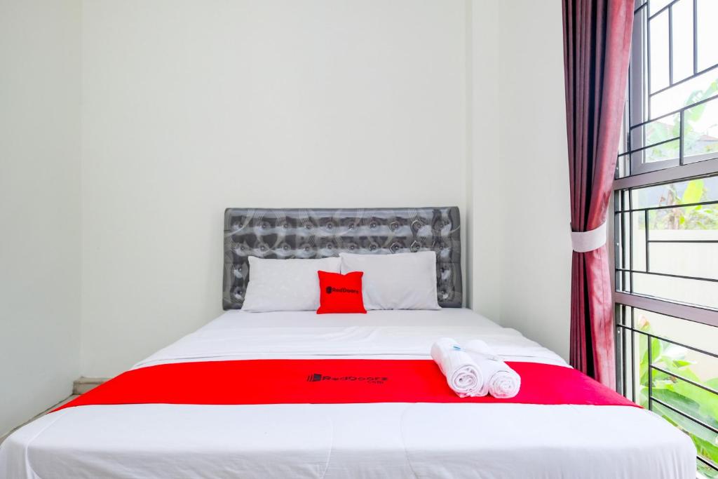 1 Schlafzimmer mit einem Bett mit einem roten Kissen und 2 Handtüchern in der Unterkunft RedDoorz Syariah near Pengadilan Agama Wonosobo in Wonosobo