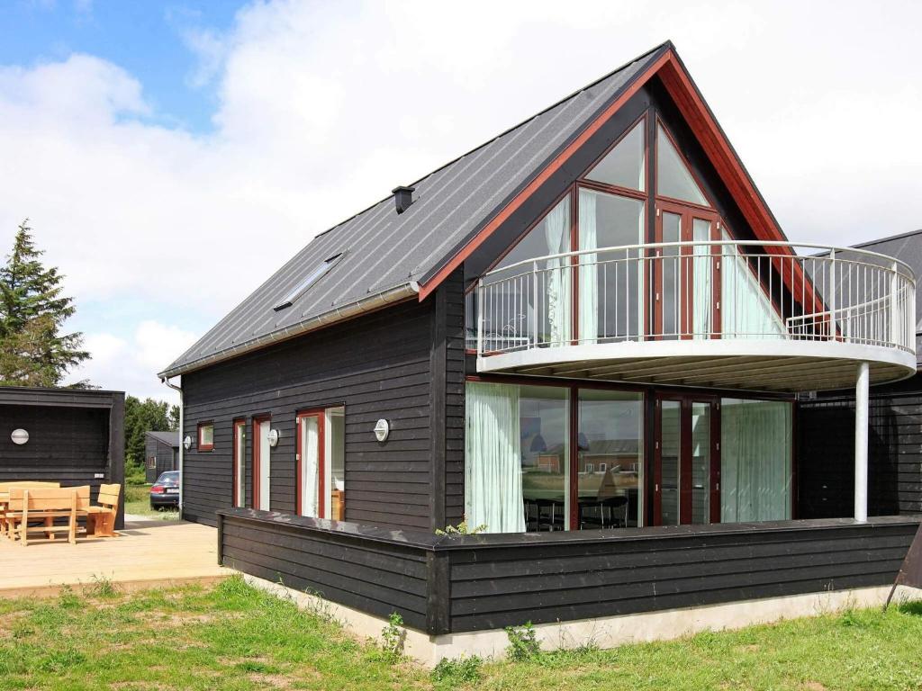 a black house with a balcony and a deck at Exclusive Golf View Retreat in Rømø Kirkeby