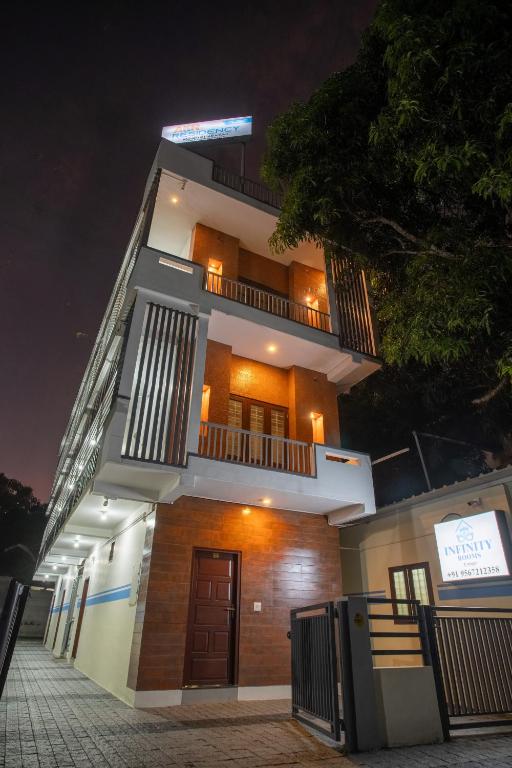 a tall building at night with a sign on it at Infinity Rooms Kazhakkoottam Technopark in Trivandrum