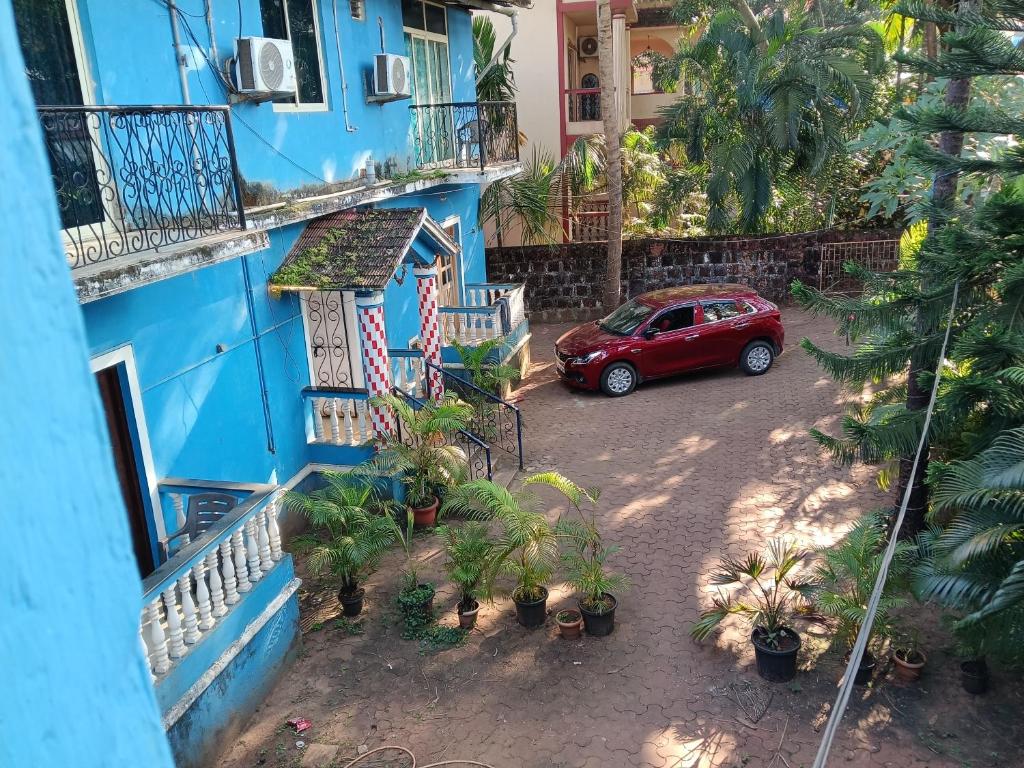 a red car parked in front of a blue building at Casa Sumanjo in Calangute