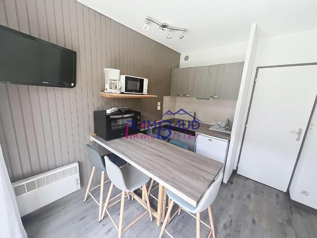 a kitchen with a wooden table with chairs and a refrigerator at Studio Cabine Rénové - 4 Couchages - Centre de Valloire - FR-1-854-46 in Valloire