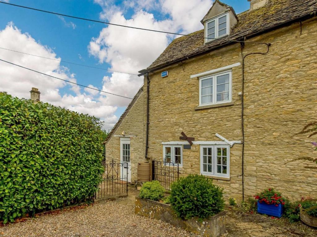 ein altes Steinhaus mit einer Hecke davor in der Unterkunft 2 bed property in Lechlade 40194 in Langford