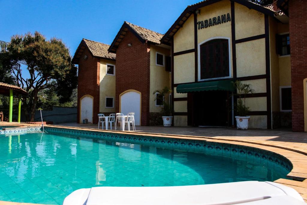 a swimming pool in front of a building at Hotel Tabarana in Serra Negra