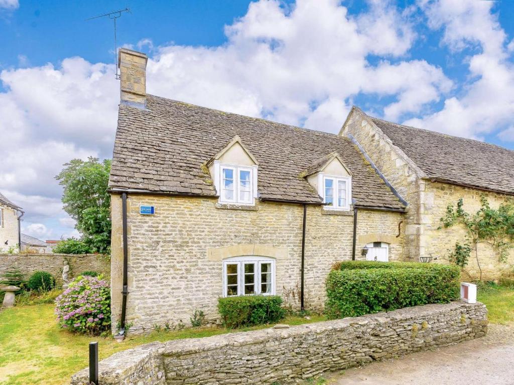 ein altes Steinhaus mit einer Steinmauer in der Unterkunft 2 bed property in Lechlade 40192 in Langford