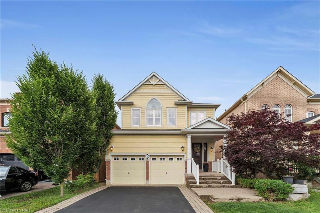 ein großes gelbes Haus mit Garage in der Unterkunft Tranquil Haven near Niagara in Thorold