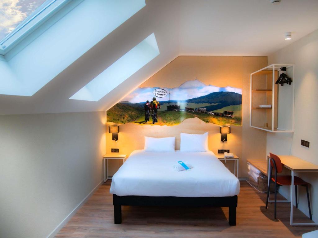 ein Schlafzimmer mit einem Bett und einem Gemälde an der Wand in der Unterkunft ibis Styles Clermont-Ferrand Aéroport in Clermont-Ferrand