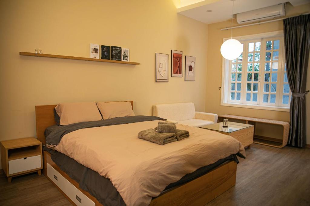 a bedroom with a bed and a chair and a window at Home Homestay in Hanoi