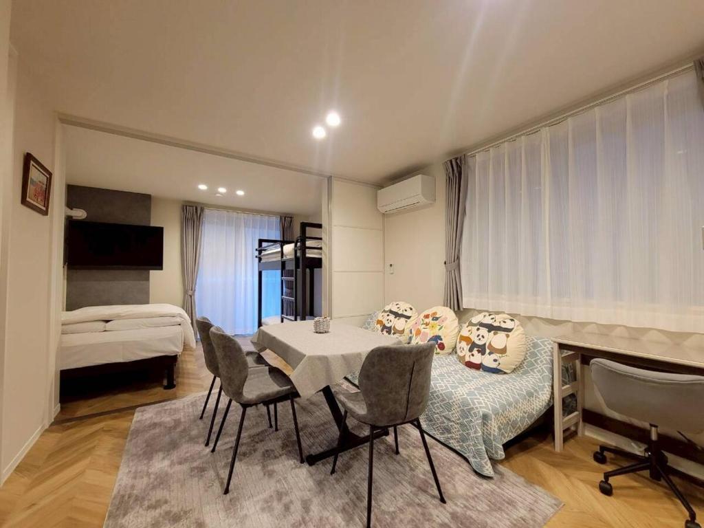 a living room with a table and chairs and a bed at ローズパーク十番館 in Narashino