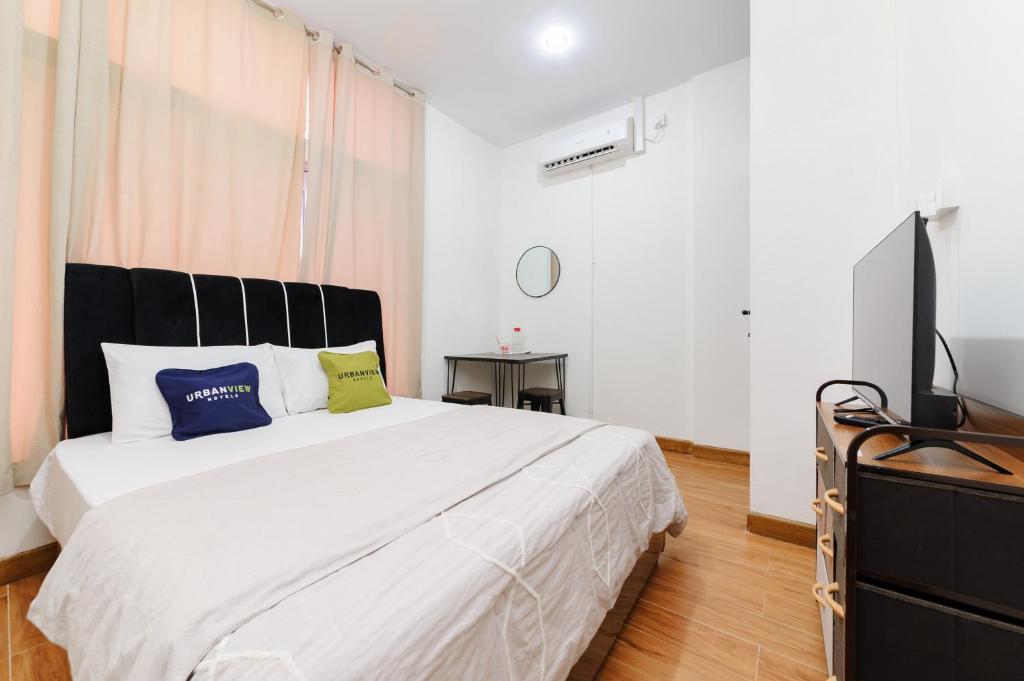 a bedroom with a large white bed and a flat screen tv at Urbanview near Mall Botania 2 in Pulau Sembakau Besar
