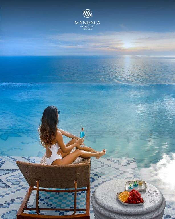 a woman sitting in a chair next to the ocean at Apec Beach Hotel Phú Yên in Phước Hậu