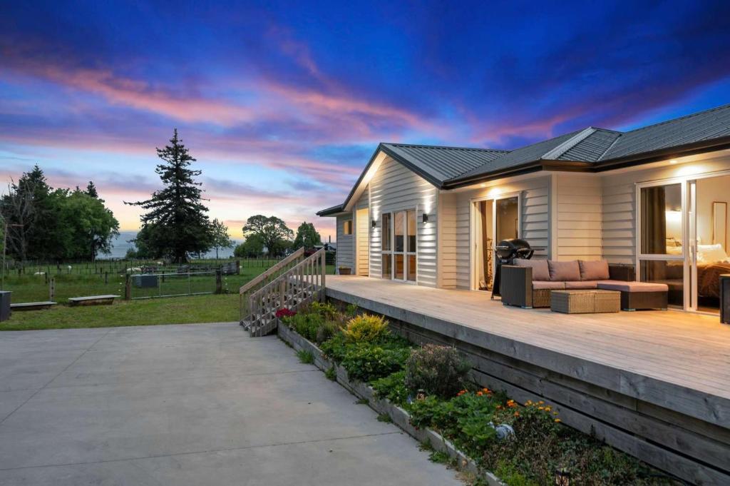 une maison avec une terrasse avec un coucher de soleil dans l'établissement Hamurana Hotspot - Walk to the Lake & Golf Course, à Hamurana