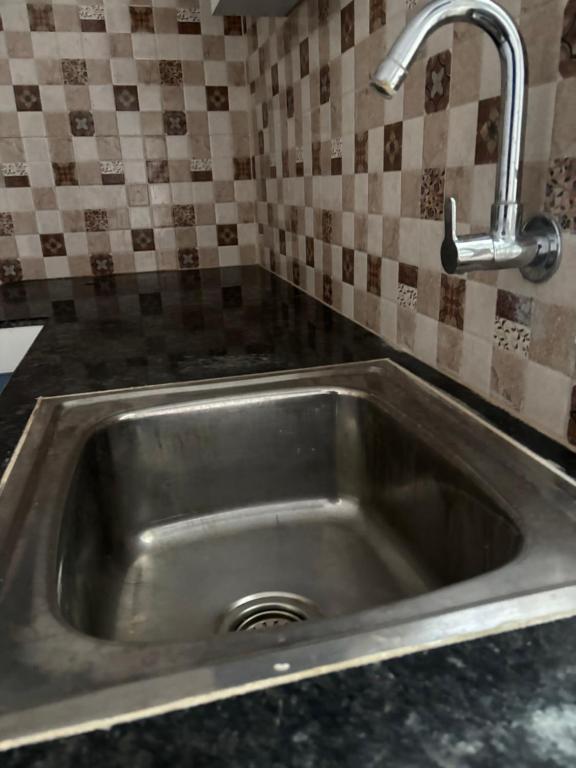 a stainless steel sink with a faucet in a kitchen at Aswin's Homestay 1bhk in Podanūr