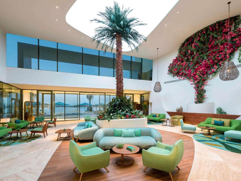 eine Lobby mit einem blauen Sofa und Palmen in der Unterkunft The Retreat Palm Dubai MGallery by Sofitel in Dubai
