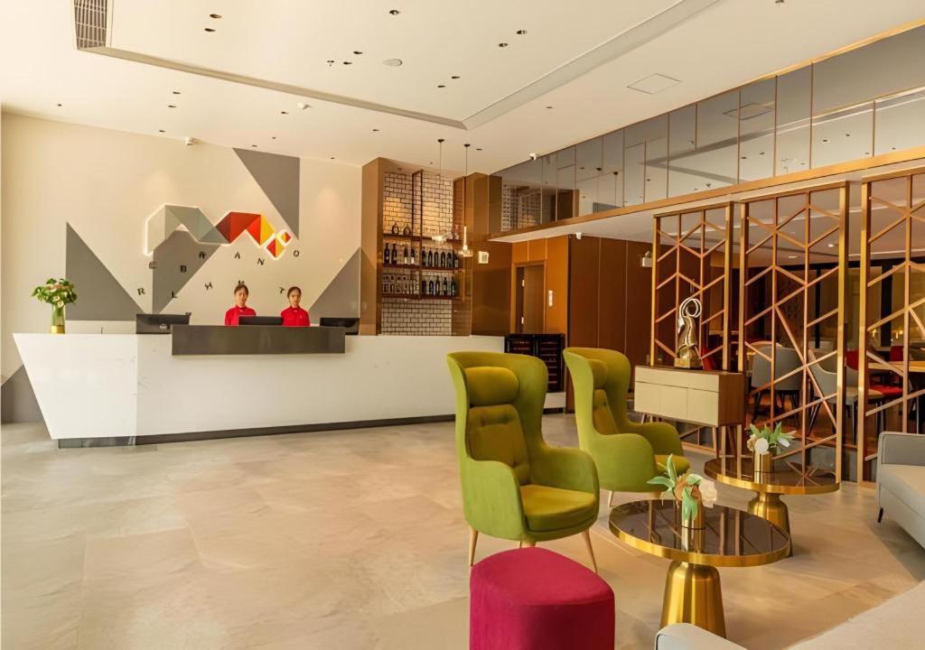 eine Lobby mit einer Bar mit grünen Stühlen und einem Tisch in der Unterkunft Borrman Hotel Dongguan Dongcheng Wanda Plaza Tianbao Metro Station in Dongguan