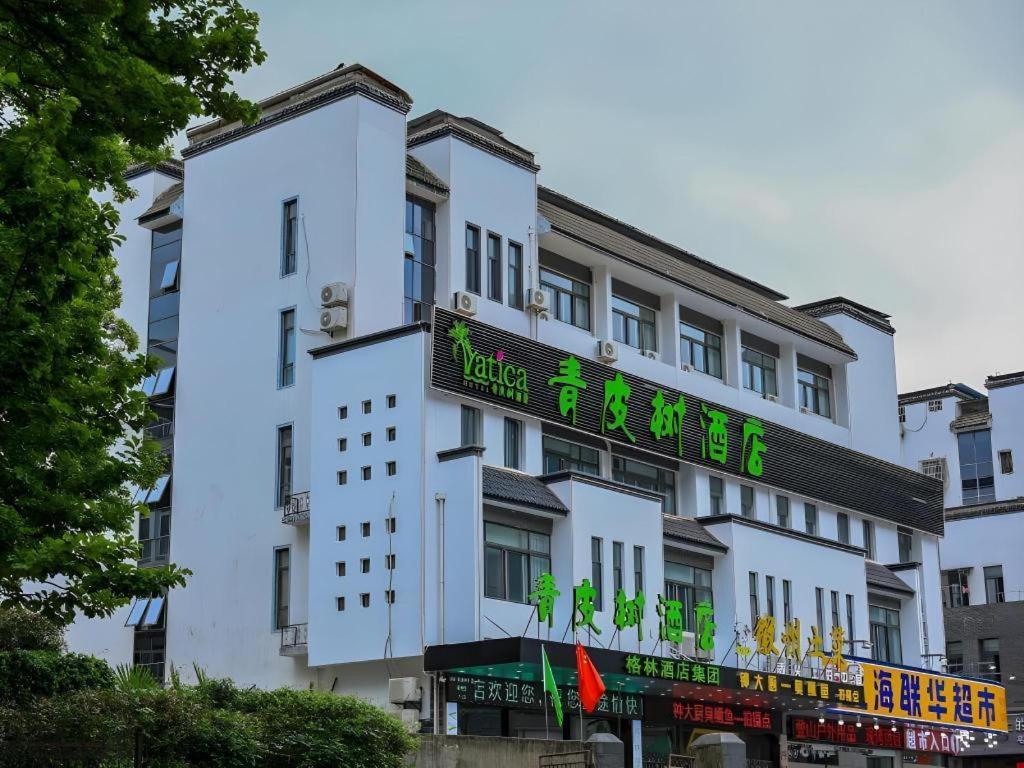 um edifício branco com um cartaz em Vatica Hotel Huangshan South Gate Terminal Station em Área Cénica das Montanhas Huangshan