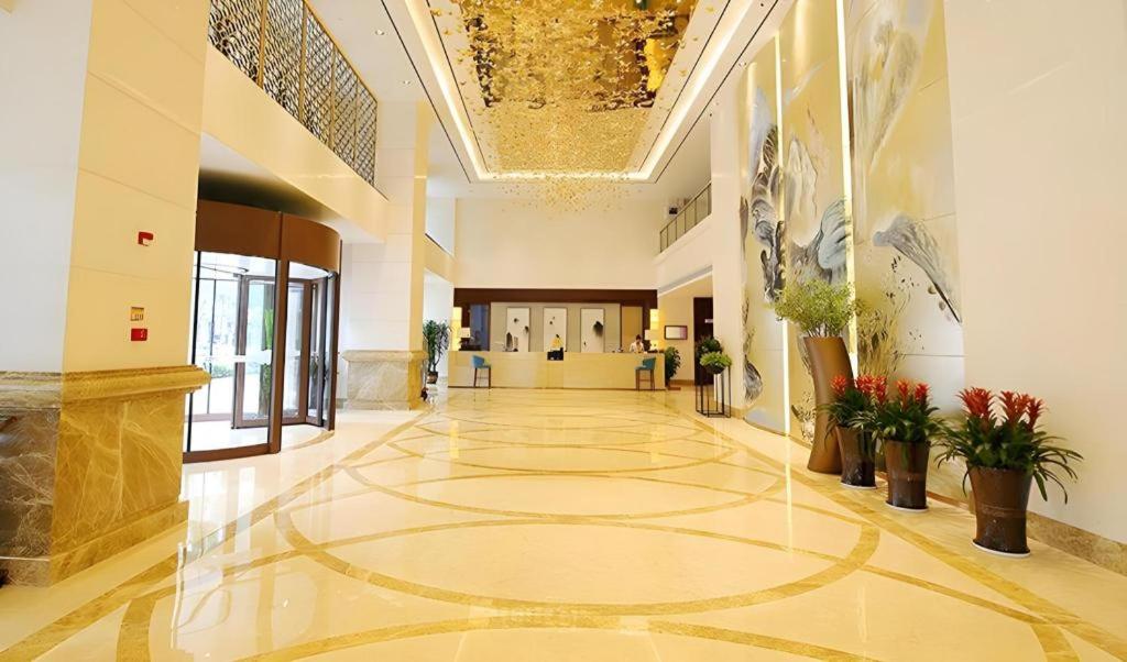 a large lobby with a large yellow tile floor at Xingtai Yuehai Hotel in Haikou