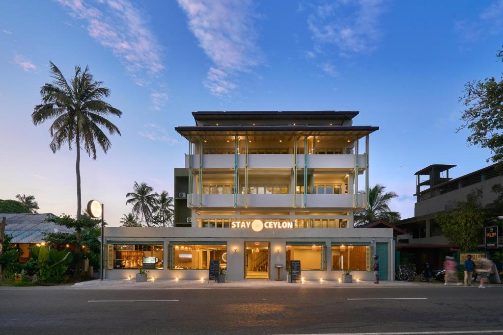 a building on a street with a palm tree at Stay Ceylon - Weligama in Weligama