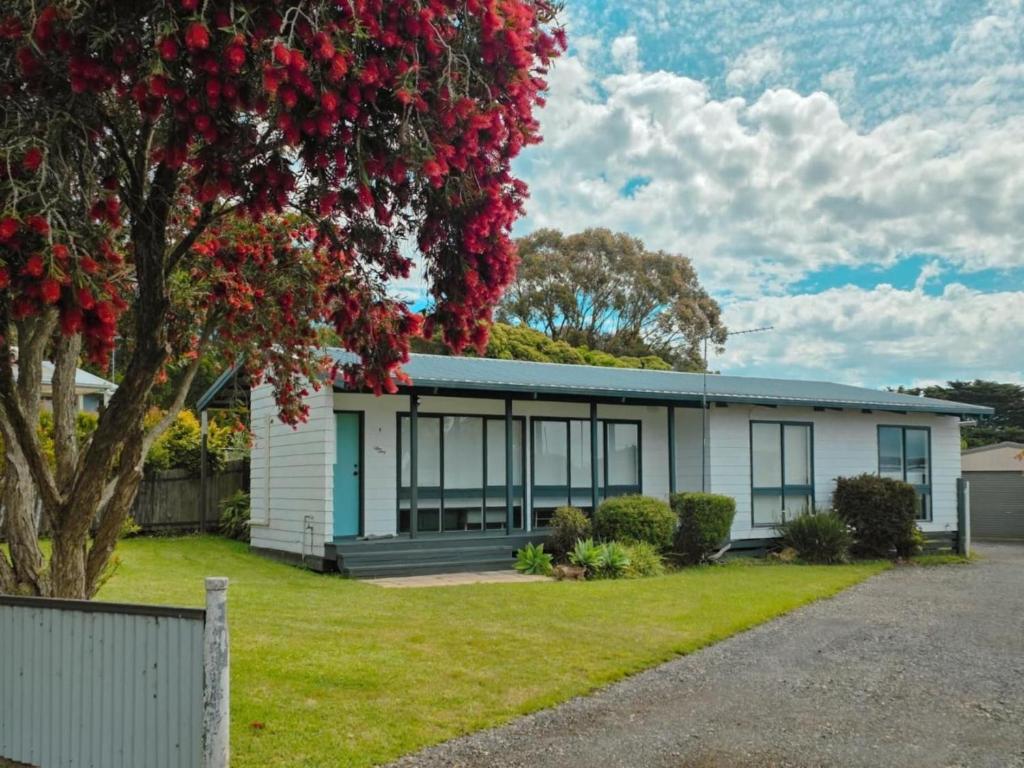 una casa con un árbol delante en Sitara Cottage, en Yanakie