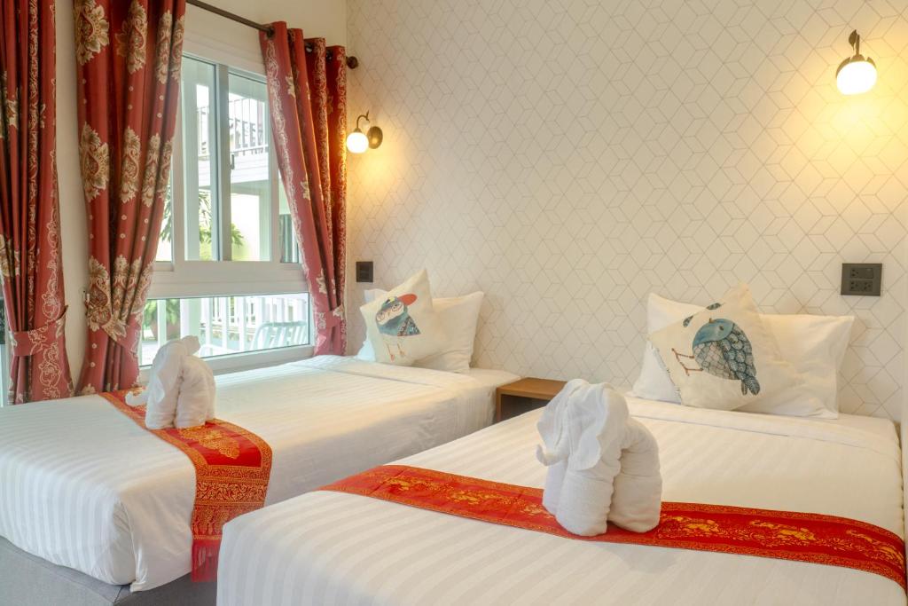 a hotel room with two beds with towels at The Golden Beach Resort Naiyang in Nai Yang Beach