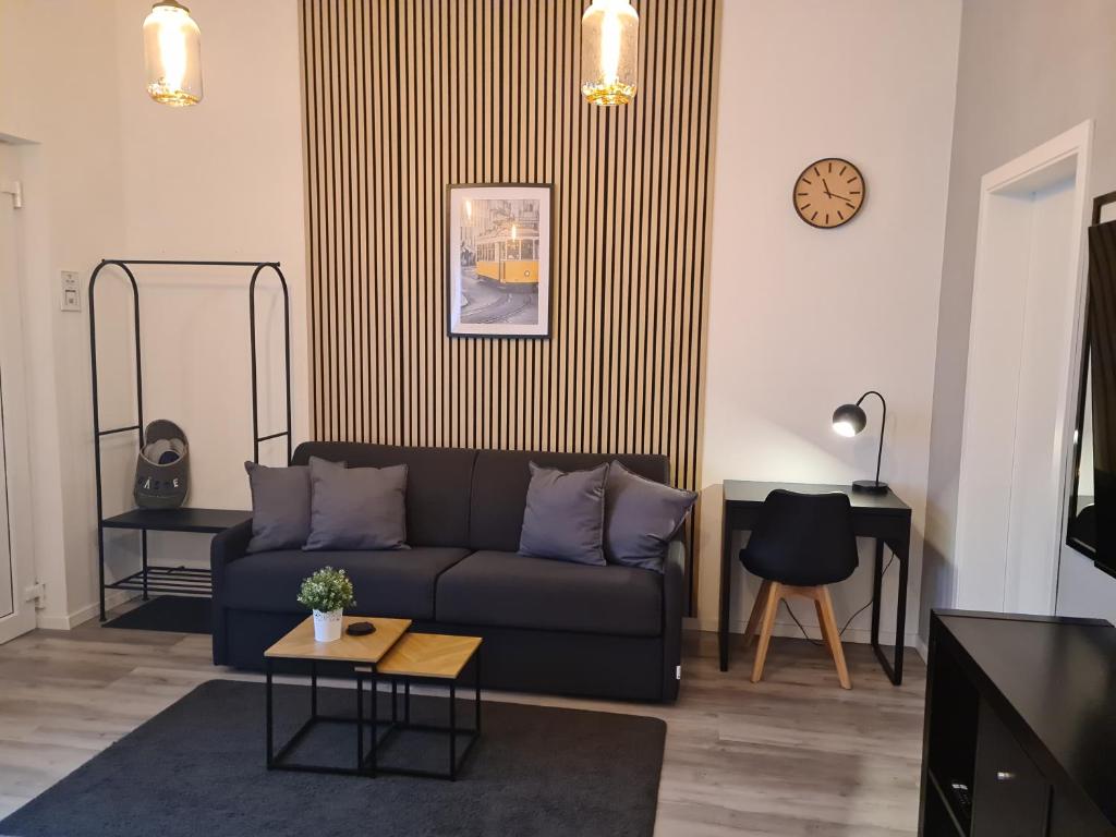 a living room with a couch and a clock on the wall at Apartmenthaus Çelik Bielefeld Süd Senne Parkplatz 24h Self Check In in Bielefeld