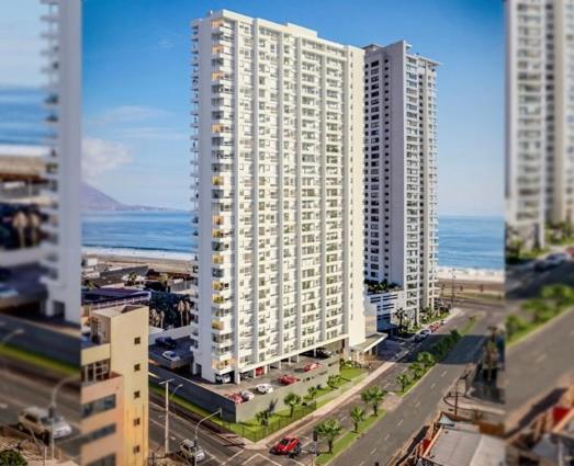 ein großes weißes Gebäude mit dem Ozean im Hintergrund in der Unterkunft Departamento completo in Iquique
