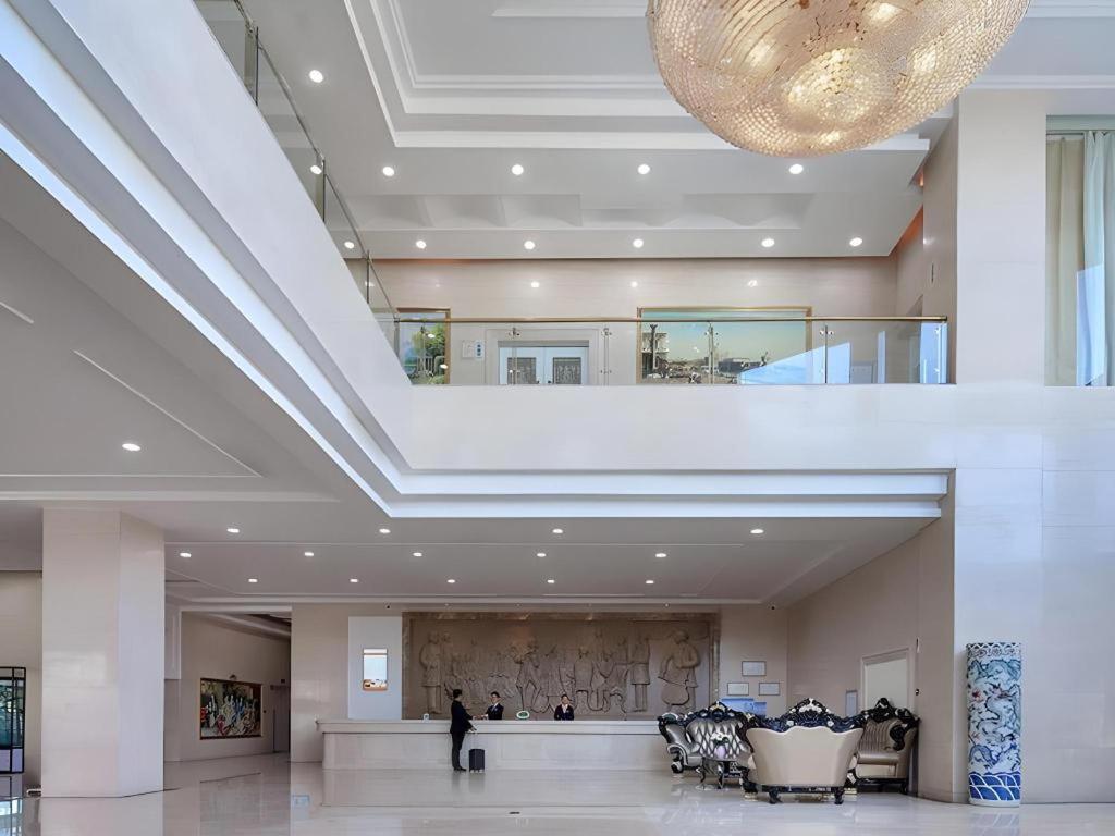 a lobby of a building with a large ceiling at Vienna Hotel Shandong Zaozhuang Qingtan Road in Zaozhuang
