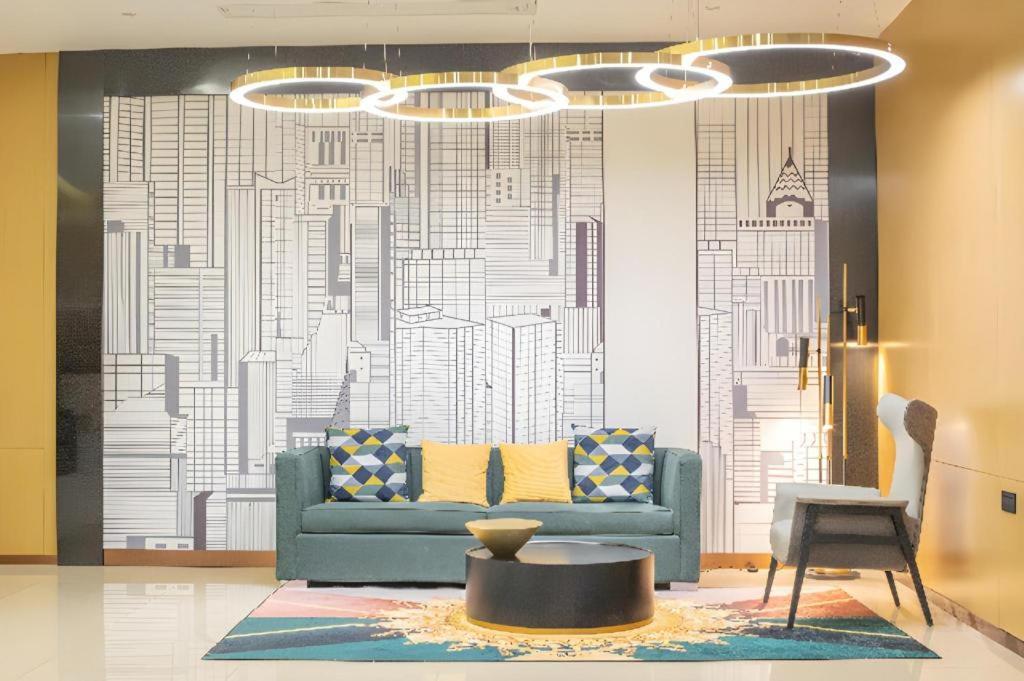 a living room with a blue couch in front of a mural at City Comfort Inn Hengyang Baishazhou in Hengyang