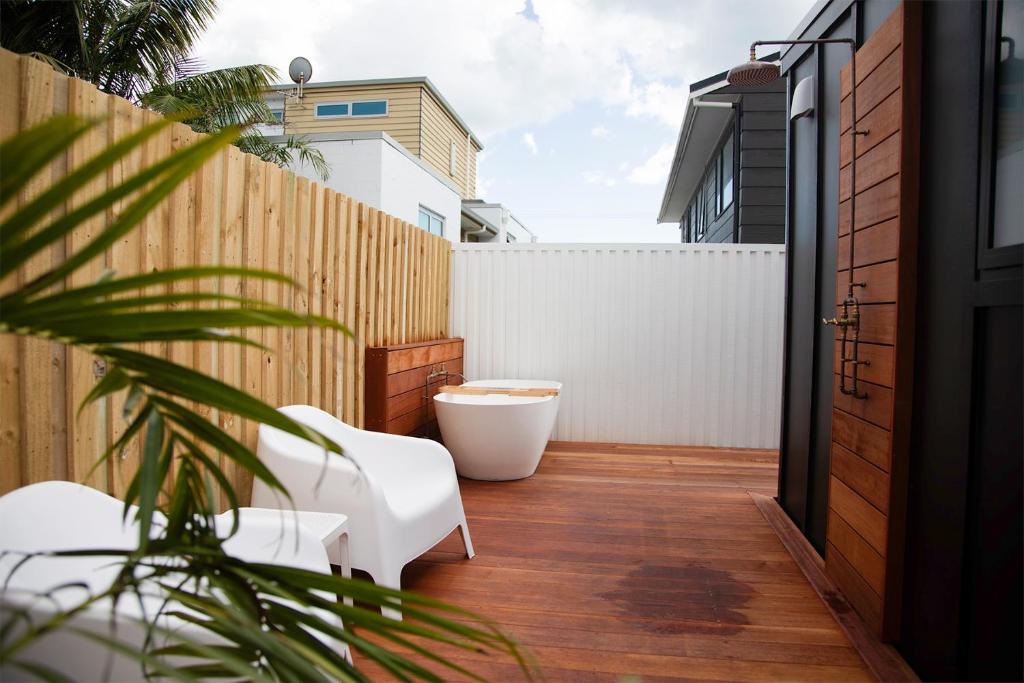 a patio with a white chair and a fence at The Coconut Hut Papamoa Beach in Tauranga