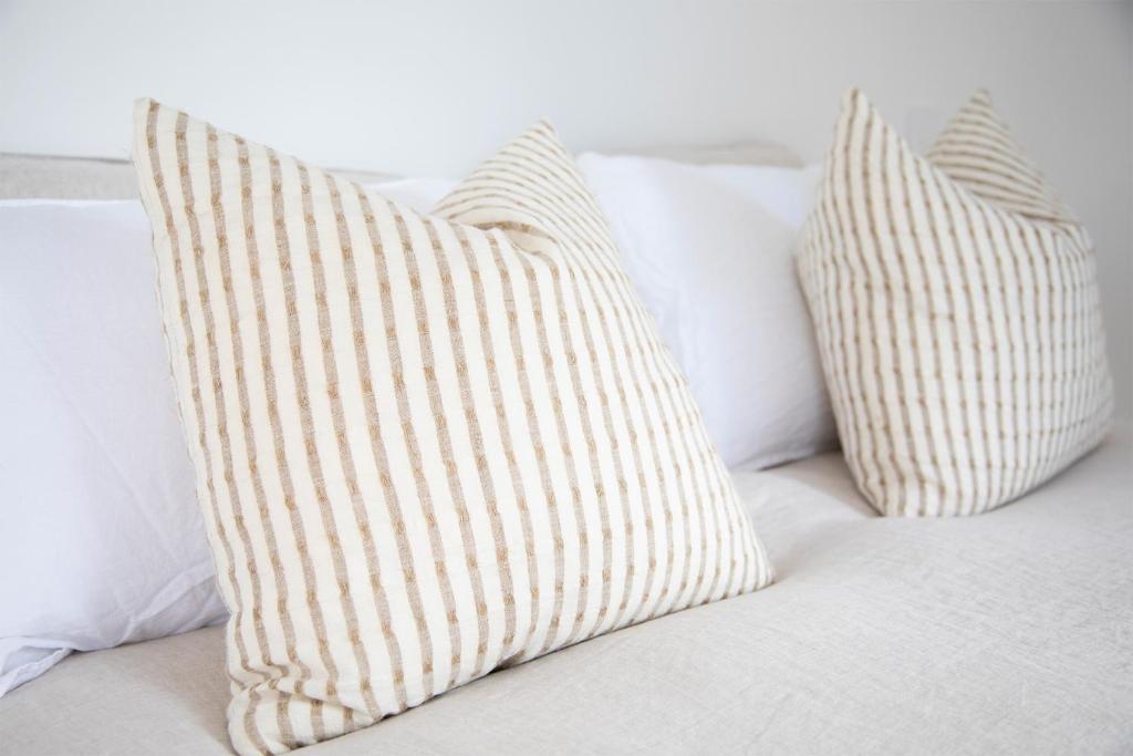 two white pillows sitting on a bed at The Coconut Hut Papamoa Beach in Tauranga