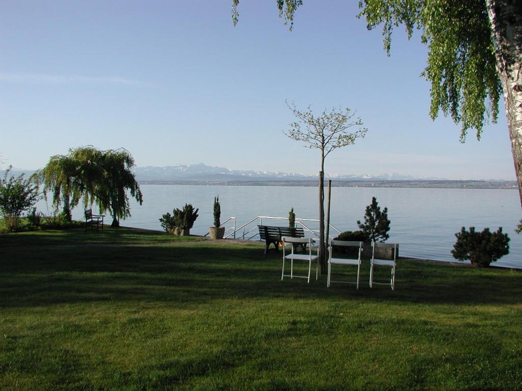 een tafel en stoelen in het gras bij het water bij Strandhaus Hagnau in Hagnau
