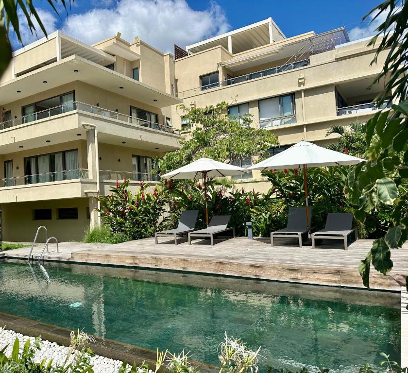 an apartment building with a pool and chairs and umbrellas at NEW Beachfront 3-bedrooms Apartment in Tamarin, Ocean Legend in Tamarin