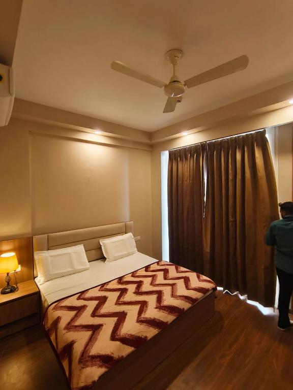 a bedroom with a bed and a person standing by a window at Street dream homestay in Greater Noida