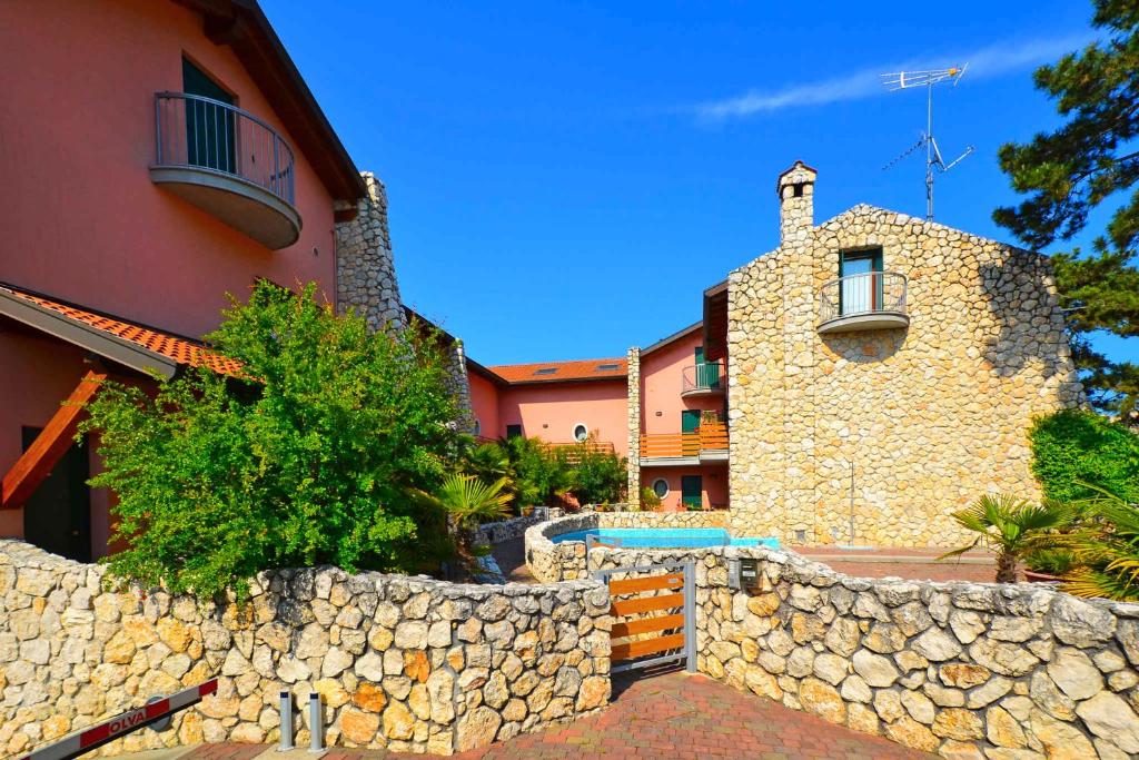 a house with a stone wall next to a building at Holiday Homes in Lignano 21665 in Lignano Sabbiadoro