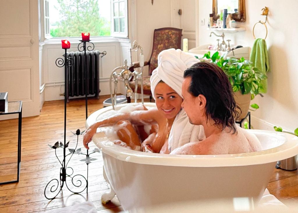 two women sitting in a bath tub at Séjour romantique ou professionnel au Château isigny, Charme et feu de cheminée in Isigny-le-Buat