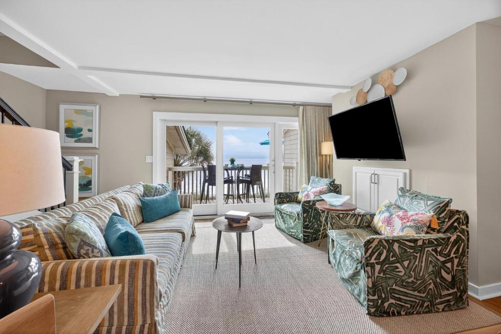 ein Wohnzimmer mit einem Sofa, Stühlen und einem TV in der Unterkunft SG10D: 10D Seagrove Villa in Isle of Palms