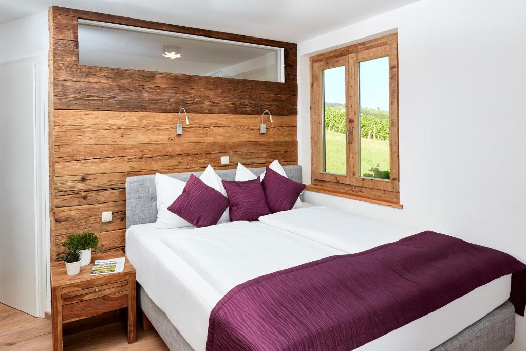een slaapkamer met een groot wit bed met paarse kussens bij Weinberg Lodge - Kellerstöckl in Klöch