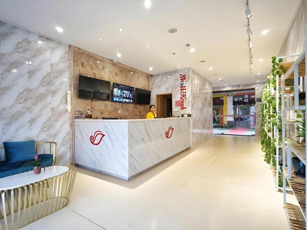 eine Person, die an einer Theke in einem Restaurant steht in der Unterkunft Shell Shanghai Baoshan District Songbin Road Subway Station Hotel in Hujiazhai