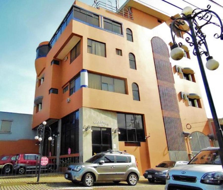 un edificio con coches estacionados frente a él en Hotel Valladolid, en Heredia