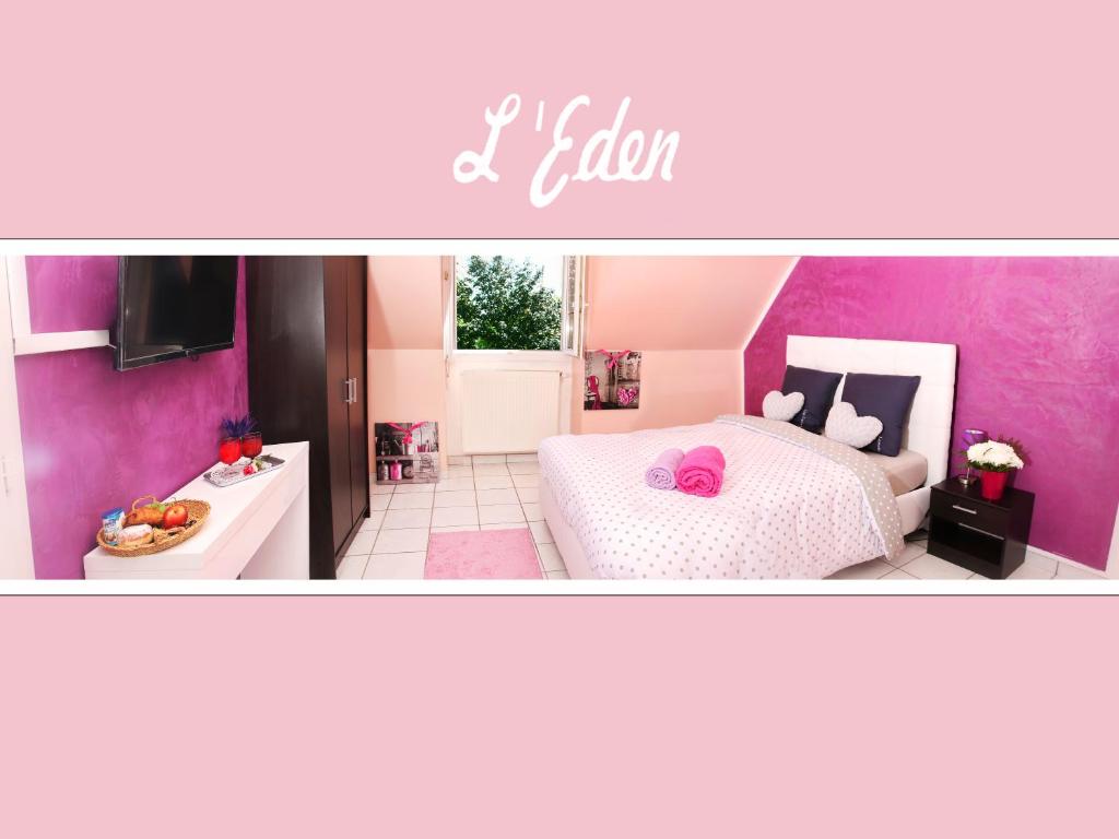 a pink bedroom with a bed and a kitchen at L'Eden Orly Aéroport in Thiais