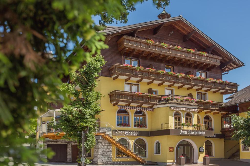 プフ・バイ・ハラインにあるHotel Gasthof Zum Kirchenwirtの花の咲くバルコニー付きの大きな黄色の建物