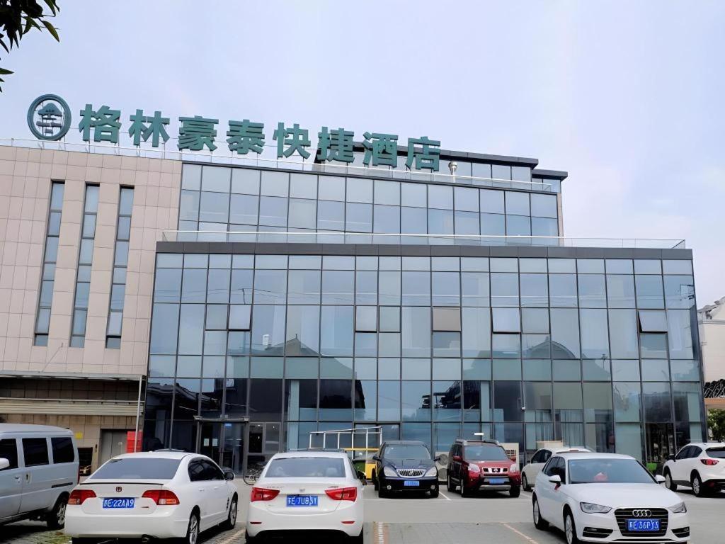 a building with cars parked in front of it at GreenTree Inn Suzhou Changshu North Haiyu Road Changhui Square Express Hotel in Changshu