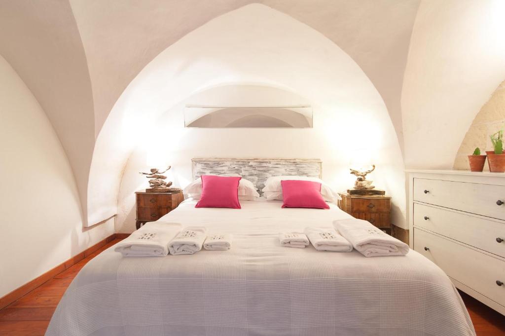 1 dormitorio con 1 cama blanca grande con almohadas rosas en Casa nei Fiori di Lecce, en Lecce