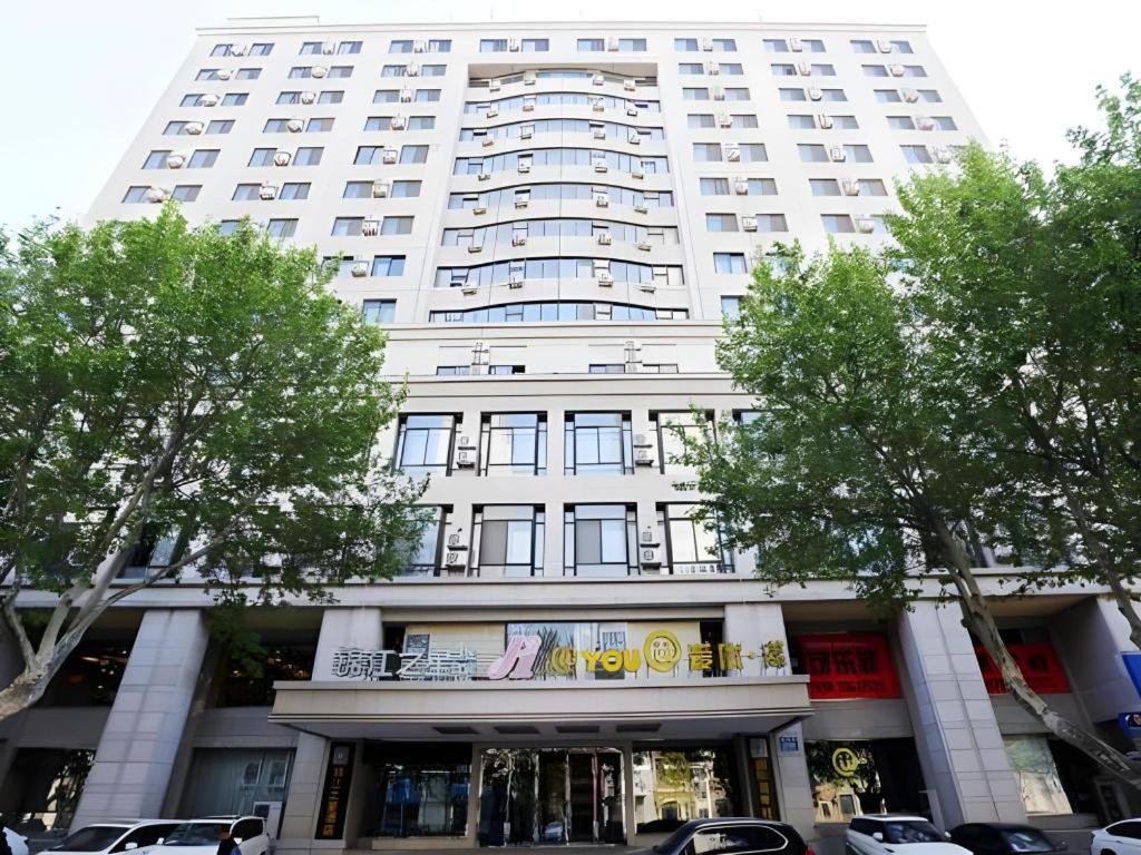 a large white building with trees in front of it at Jinjiang Inn Dalian Jiefang Road in Dalian