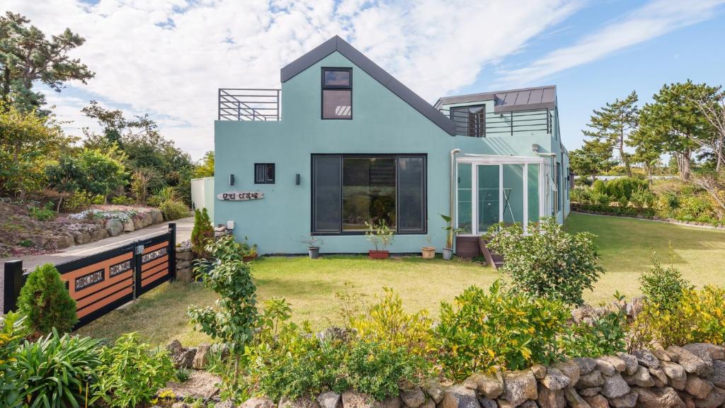 a blue house with a yard at Jeju moridarakbang pension in Jeju