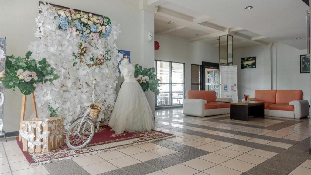 a room with a wedding dress and a wall with flowers at d'Arcici Hotel Plumpang in Jakarta