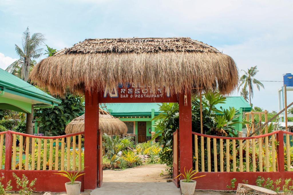 un complejo con un paraguas de paja y un edificio en Moonlight Resort, en Isla de Malapascua