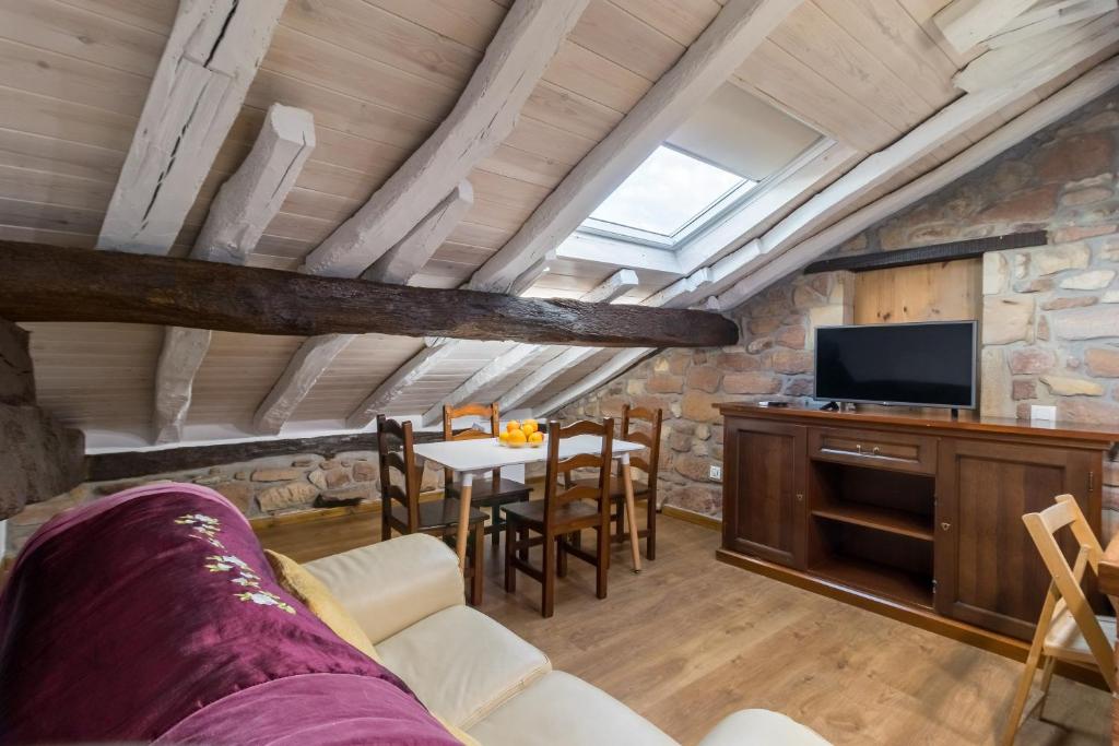 ein Wohnzimmer mit einem TV und einem Tisch mit Stühlen in der Unterkunft Casa Velarde Apto 2 in Viérnoles