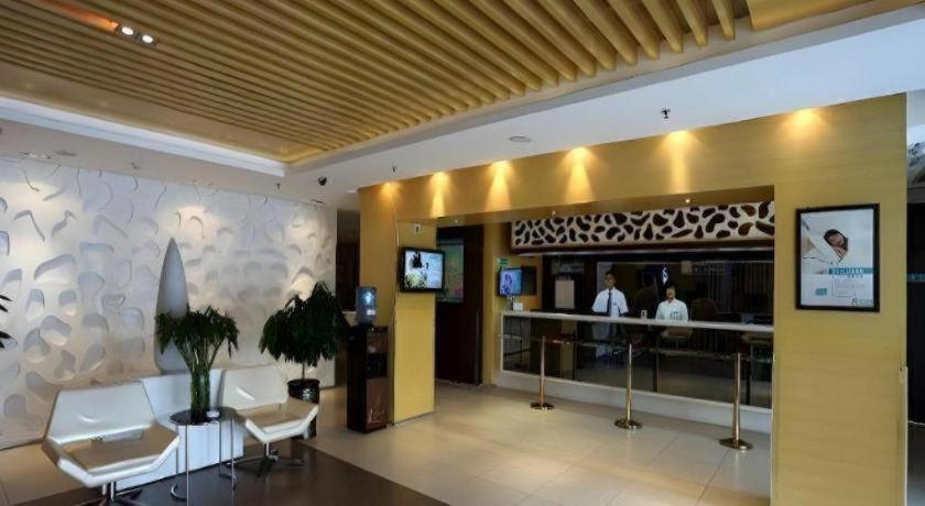 a lobby of a hotel with white chairs and a counter at Jinjiang Inn Jinzhou Luoyang Road in Jinzhou