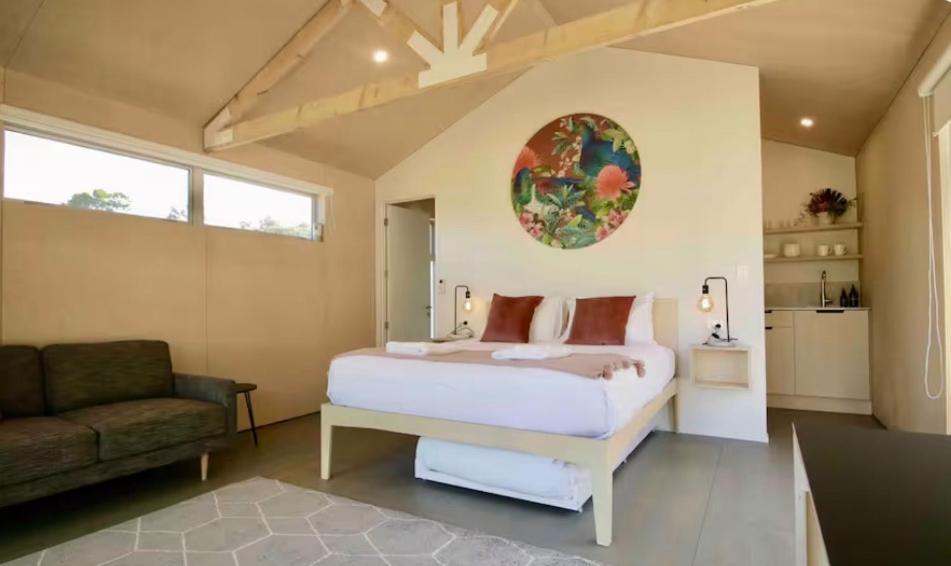 a bedroom with a bed and a chair and a couch at One O One Cabins, Waiheke Island in Oneroa