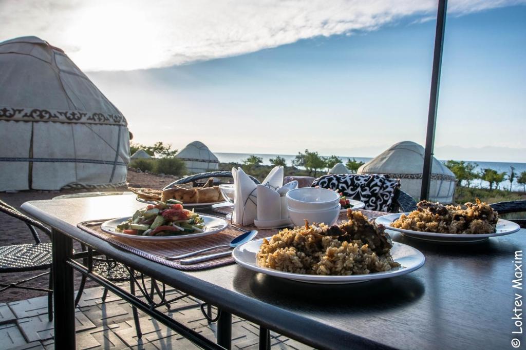 einen Tisch mit Teller mit Speisen auf einem Tisch am Strand in der Unterkunft Oimo Tash Yurt Camp in Kaji-Say